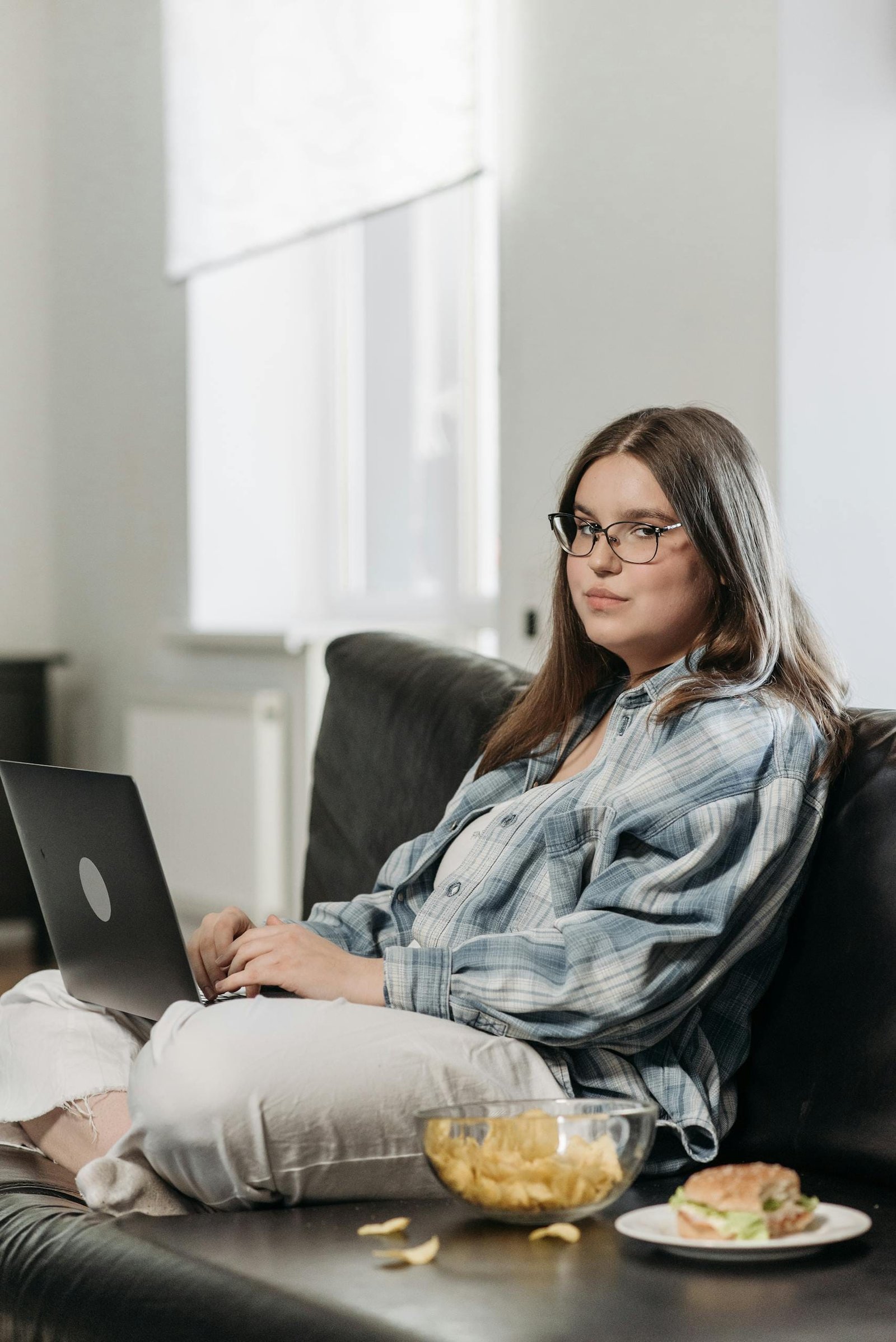 A Woman Sitting on the Sofa while Using a Laptop