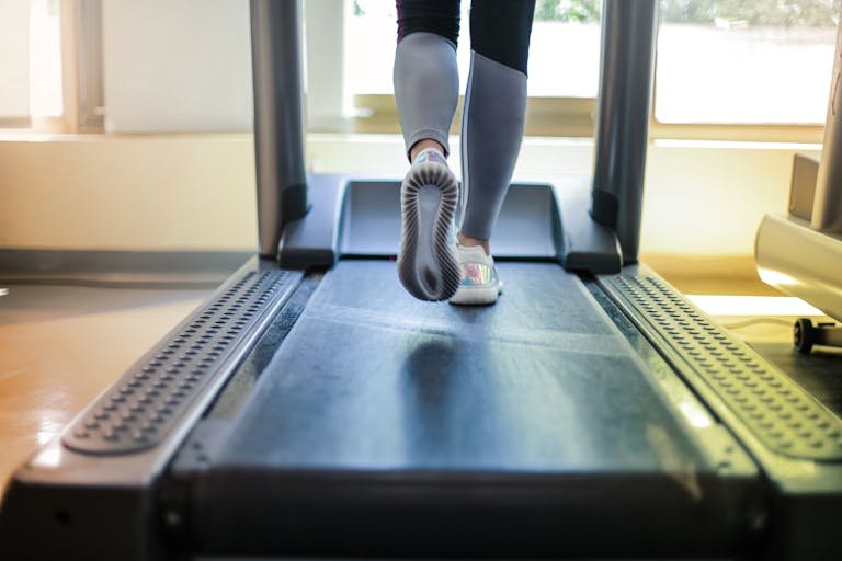 Close-up shot of a person exercising on a treadmill, showcasing fitness and health focus.