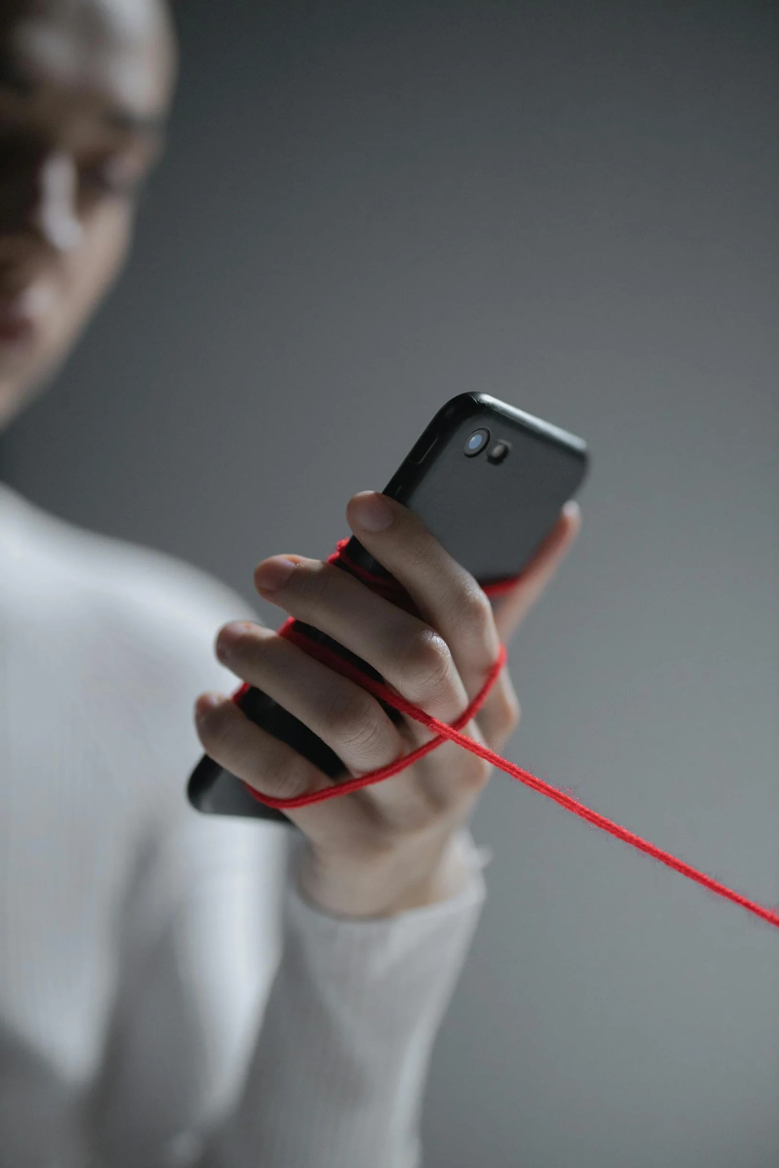 Une main tenant un smartphone avec fil rouge, symbolisant l'impact des réseaux sociaux sur l'image corporelle et les TCA