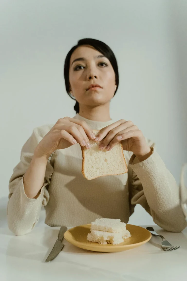Femme face à une tranche de pain, illustrant restriction alimentaire et compulsion alimentaire