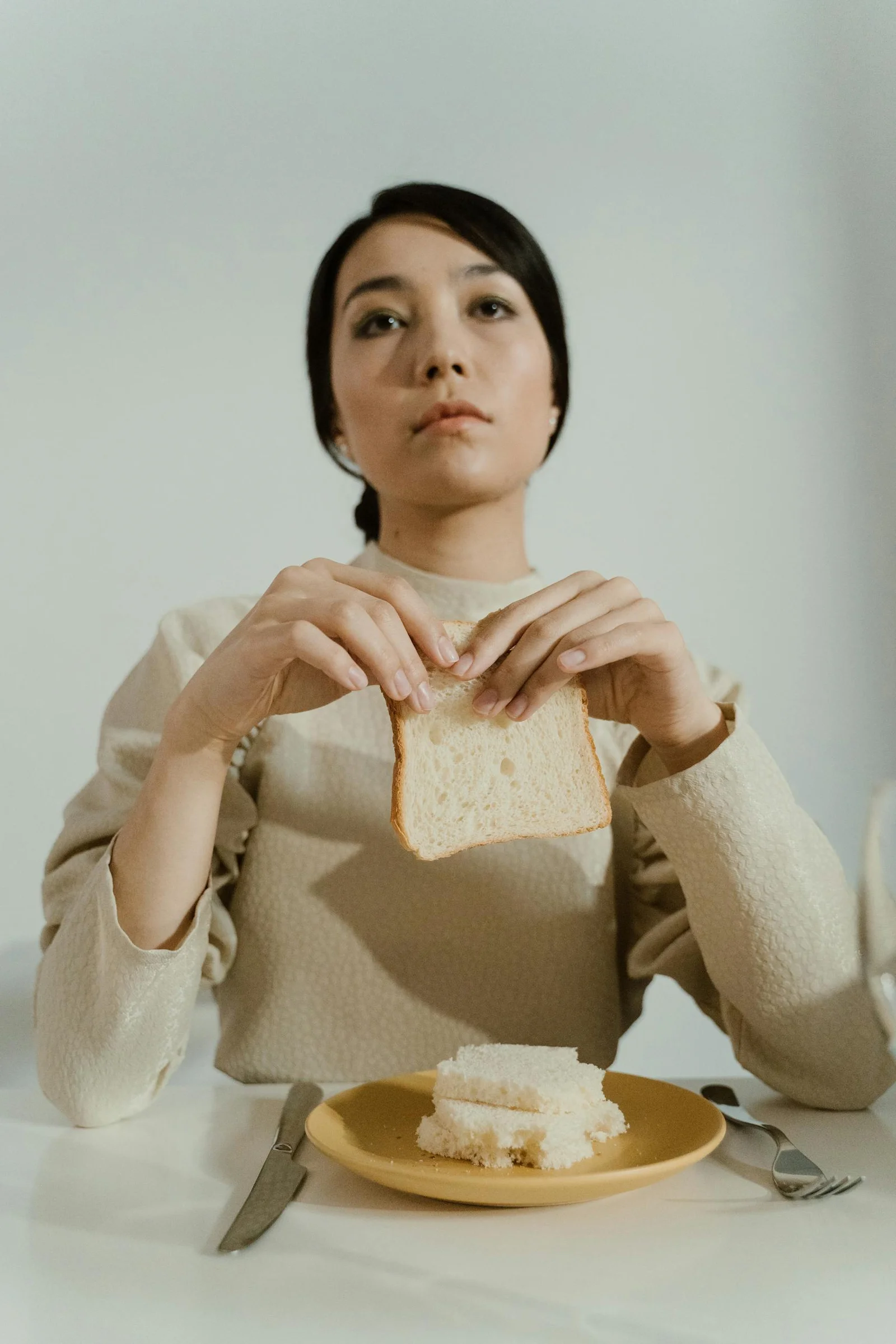 Femme face à une tranche de pain, illustrant restriction alimentaire et compulsion alimentaire